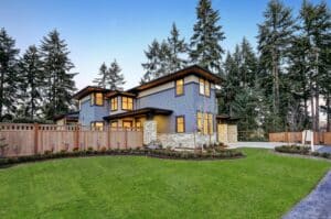 A modern two-story home with stone and wood siding surrounded by mature evergreen trees on a landscaped lot, typical of Bellevue Eastside residential properties.