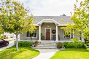 A small Seattle home with healthy, vibrant trees in the front yard during summer.