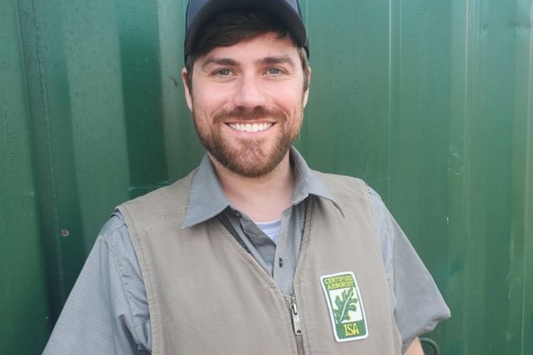 A certified arborist of Seattle Tree Care on a vest with a logo of ISA over a green background