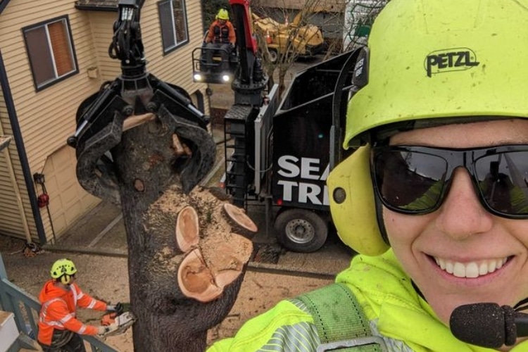Seattle Tree Care crew doing a selfie while doing a tree removal using a grapple-claw truck on a property near Seattle.
